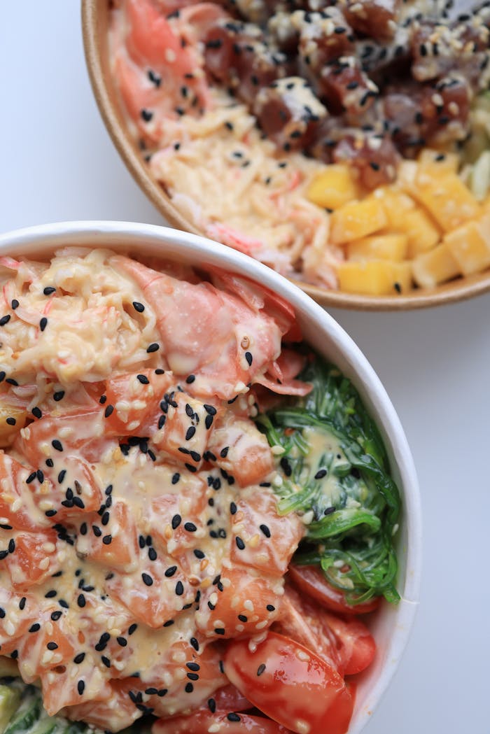 heros-img Delicious poke bowls with fresh salmon, tuna, mango, and seaweed, topped with sesame seeds.